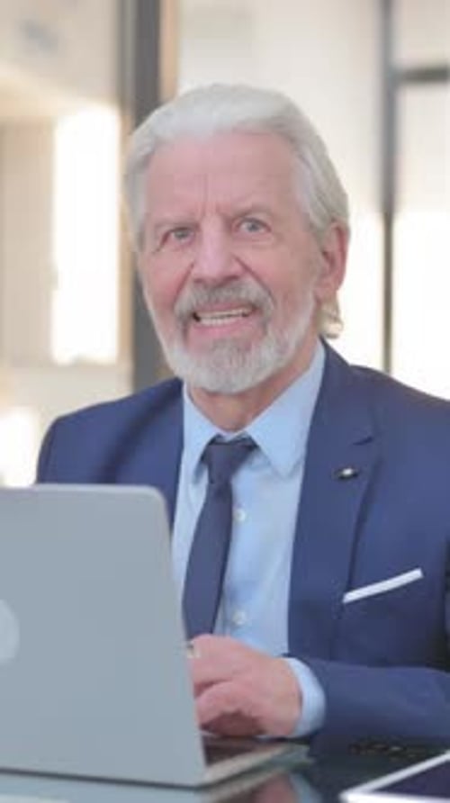 Old Businessman Smiling at Camera while Working in Office, vertical video