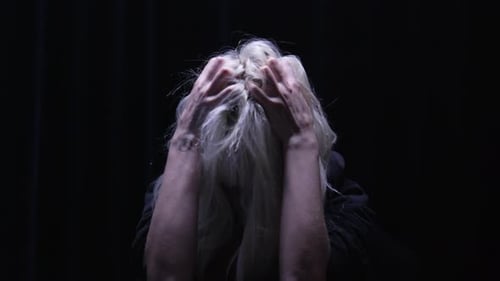 Blonde Woman Pulls at Hair in Dark Room