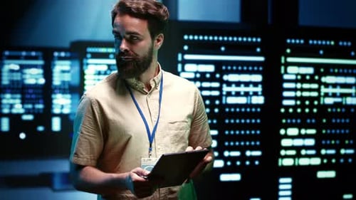 Man Uses Tablet in Front of Wall of Servers
