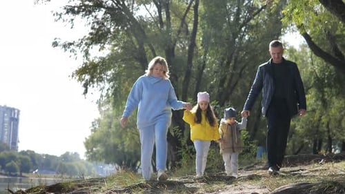 Young Couple of Grandparents with Two Little Grandkids Walking Along River Shore Holding Hands in