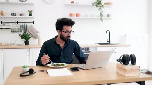 Man Working on Laptop While Eating Salad