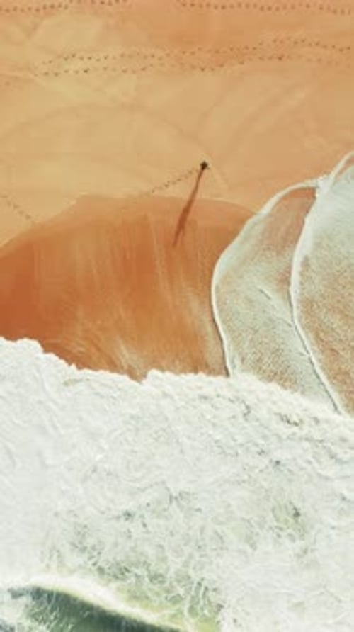 A Serene Video of a Man Fishing Alone at the Beach with Highdefinition Aerial View