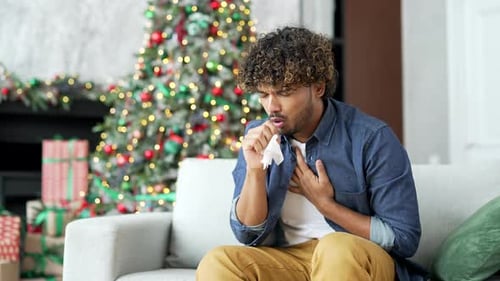 Man With Cold Sitting Near Christmas Tree