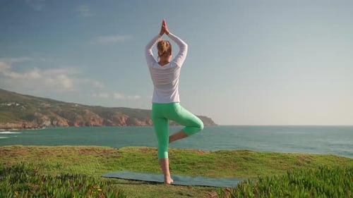 Mature Woman Practicing Yoga Tree Pose Vrikshasana Near Sea on Beach