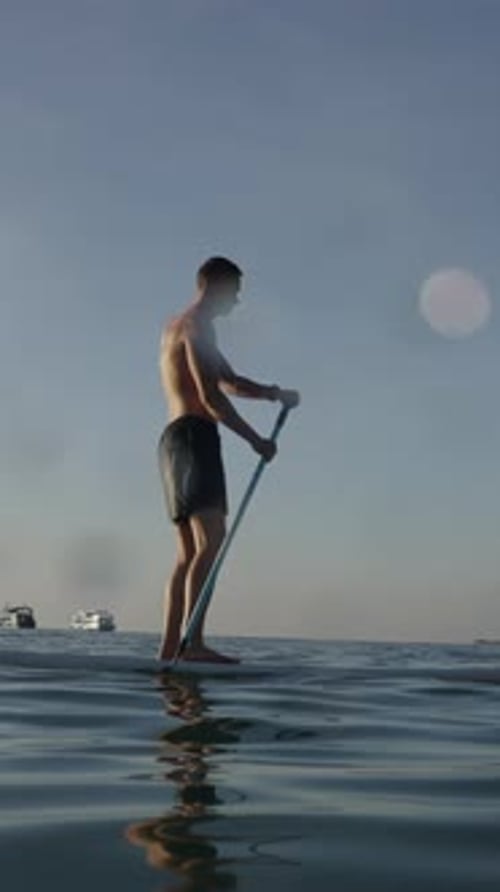 Western Man Paddling Atop His Paddle Surfboard on the Sea