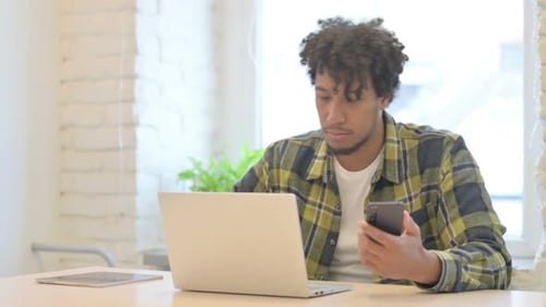 Young Adult Working at Desk With Mobile Phone