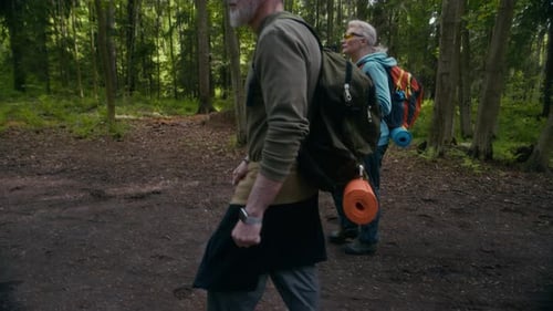 Sportliches älteres Wanderpaar, das den Waldweg entlang geht