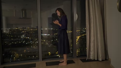 Woman Using Phone Near Window at Night