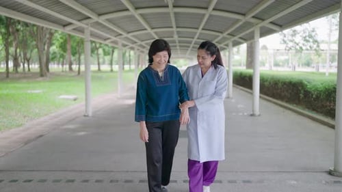 Woman Assisted by Medical Professional Walking Outside