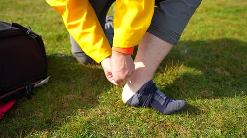 Hiker takes off sock to put adhesive pad to prevent heel chafing. Hiking in Faroe Islands. Closeup