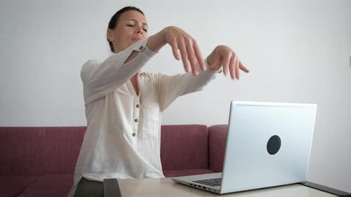 Woman Stretches Wrists after Typing at Laptop