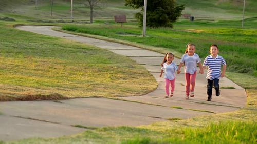 Three happy latino children friends siblings playing and enjoying running together holding hands