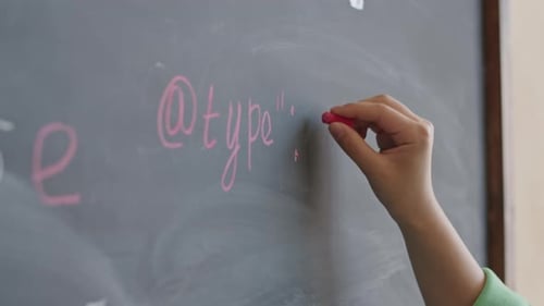 Hand Writes with Chalk on Chalkboard in Classroom
