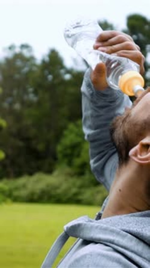Man Drinking Water Outside on Green Lawn