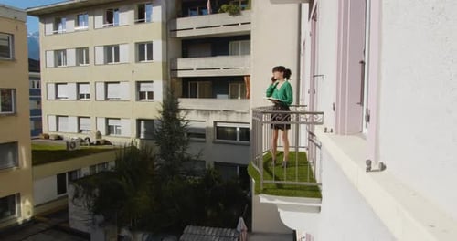 Brunette woman having a phone call from her balcony