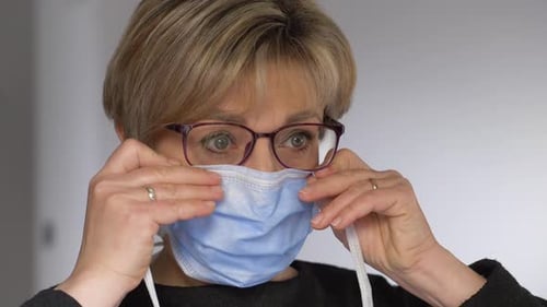 Woman Puts on Blue Surgical Face Mask