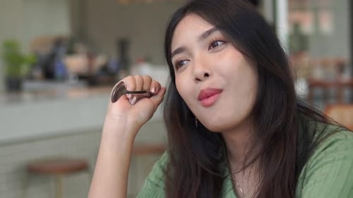 Woman Eats Dessert at Bright Cafe Table