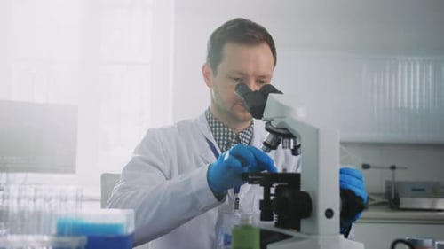 Male Scientist Using Microscope for Research in Laboratory