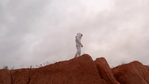 Astronaut Looking Around Standing at Top Hill on Far Planet Surface
