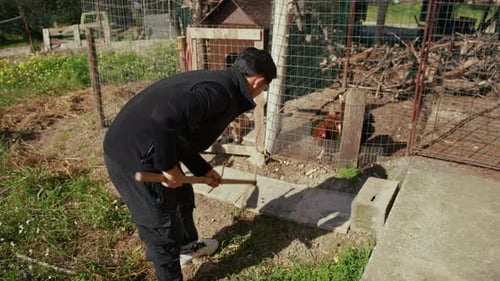 Un homme nettoie le bord d'un trottoir avec une houe