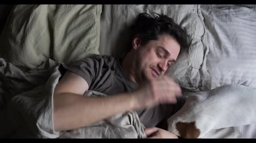 Man Awakes in Bed, Affectionate with Pet Dog