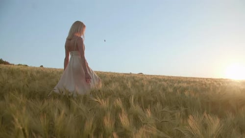 Woman Walks Through Wheat Field at Sunset