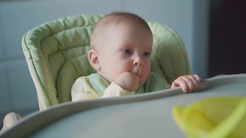 Blond Infant Sits in Green High Chair