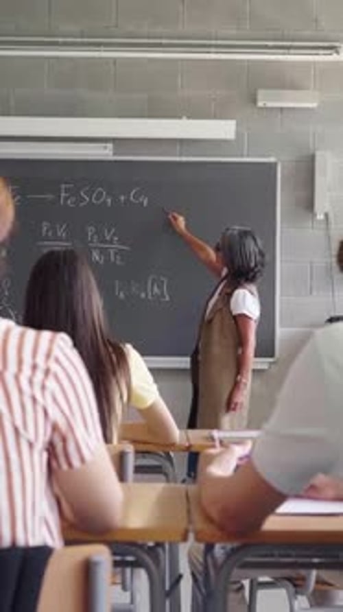Teacher Explaining Chemistry Formulas to Students in a Classroom Setting at University School