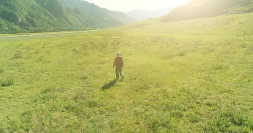 Flight Over Backpack Hiking Tourist Walking Across Green Mountain Field Huge Rural Valley at Summer