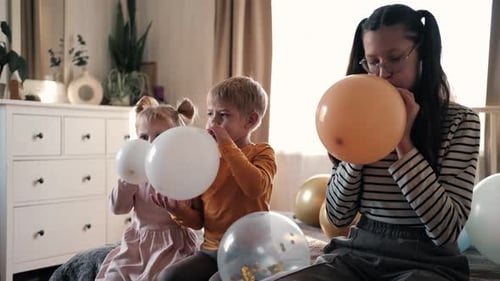 Children Inflate Colorful Balloons on Bed Together