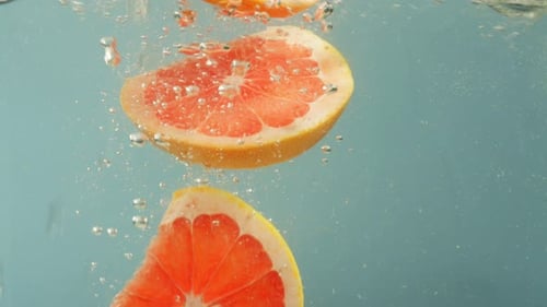 Grapefruit Slices Falling into Water with Bubbles