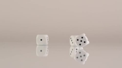 Hand Drops Dice on Reflective Surface