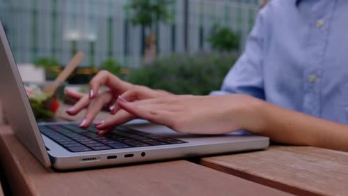 Gros plan des mains d'une femme d'affaires tapant sur un ordinateur portable assise à l'extérieur