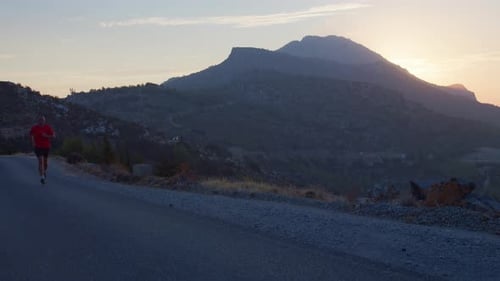 Man Running on Road at Sunrise in Mountains