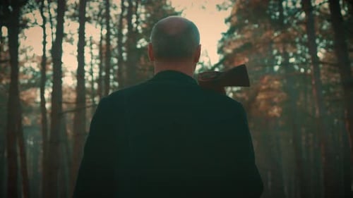 Adult Man Horror of Maniac Killer Walking Through Dark Forest with Axe in Hand