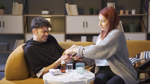 Sick Man Taking Pills While Woman Provides Care