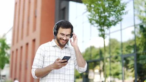Man with Headphones Using Smartphone in City