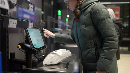 Das Mädchen scannt die Ware an der Selbstbedienungskasse und bezahlt den Kauf per Telefon