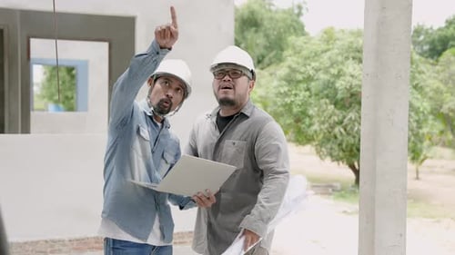 Asian engineers in helmet discuss about stringer construction. Construction man explain building pla
