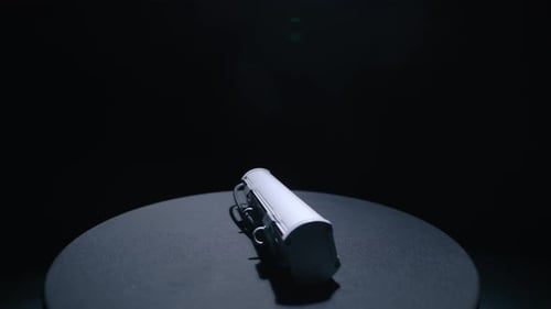 Der Luster mit LED-Röhren dreht sich auf dem Ständer im dunklen Studio