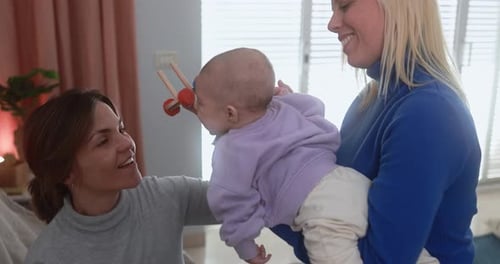 Two Women Playing with Infant at Home