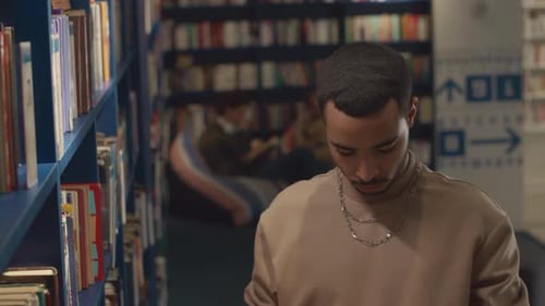 Young Middle Eastern Guy Choosing Books in University Library