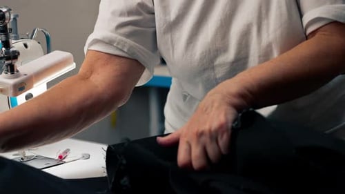Close Up in a Sewing Workshop on a Machine the Old Seamstress Master Makes Cut on a Black Fabric