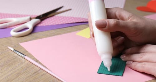Woman Crafts Paper Card with Glue and Scissors