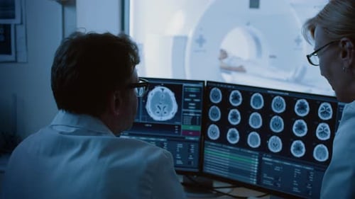 In Medical Laboratory Patient Undergoes MRI or CT Scan Procedure, in Control Room Doctor and Radiol
