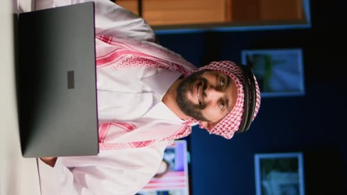 Man in Robe Using Laptop at Night