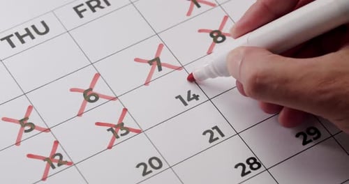 Person, die Termine in einem Kalender mit einer roten Markierung markiert (Nahaufnahme)