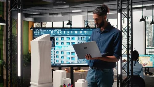 Architect Using Laptop Next to Building Model