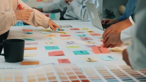 Team Collaboration in Creative Workshop with Color Swatches and Sticky Notes Laying on Table Surroun