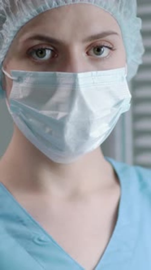 Portrait of Nurse in Mask, Scrubs and Cap at Work in Clinic